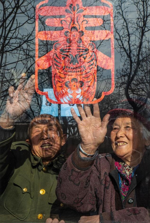 臘月里，霍州市師莊鄉(xiāng)馮南垣村村民師榮光(左)在災(zāi)后重建的新家里貼窗花。(霍州市委宣傳部供圖)