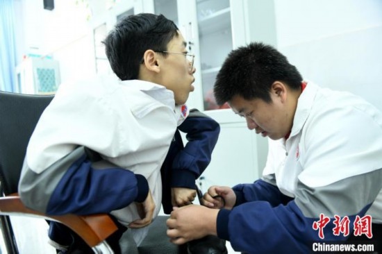 江西省南康中學(xué)北校區(qū)的高三學(xué)生朱金祥(右)正在給鐘華強(qiáng)(左)系好鞋帶。 卓忠偉 攝