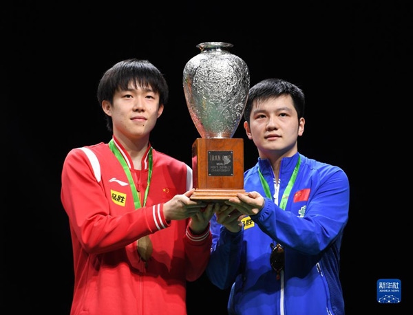 5月27日，樊振東（右）/王楚欽在頒獎(jiǎng)儀式上高舉獎(jiǎng)杯慶祝。當(dāng)日，在南非德班進(jìn)行的2023年世界乒乓球錦標(biāo)賽男雙決賽中，中國組合樊振東/王楚欽以3比0戰(zhàn)勝韓國組合張禹珍/林鐘勛，奪得冠軍。新華社記者 李亞輝攝