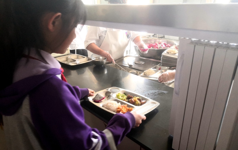 伊金霍洛旗第一小學(xué)學(xué)生正在打飯，今天的飯菜是三菜一湯外加水果，學(xué)生可以多次盛取，吃飽為止。人民網(wǎng)記者 孫博洋攝