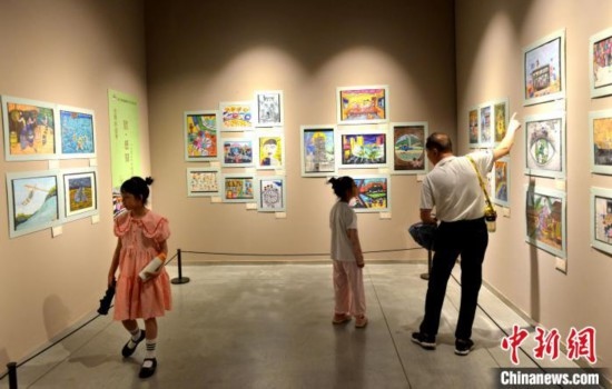 圖為家長(zhǎng)帶著孩子參觀展覽。呂明 攝