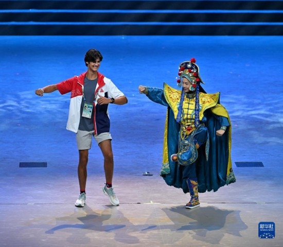 7月29日，美國運動員杜恩（左）在聯(lián)歡會現(xiàn)場與川劇演員互動。新華社記者 蔡湘鑫 攝