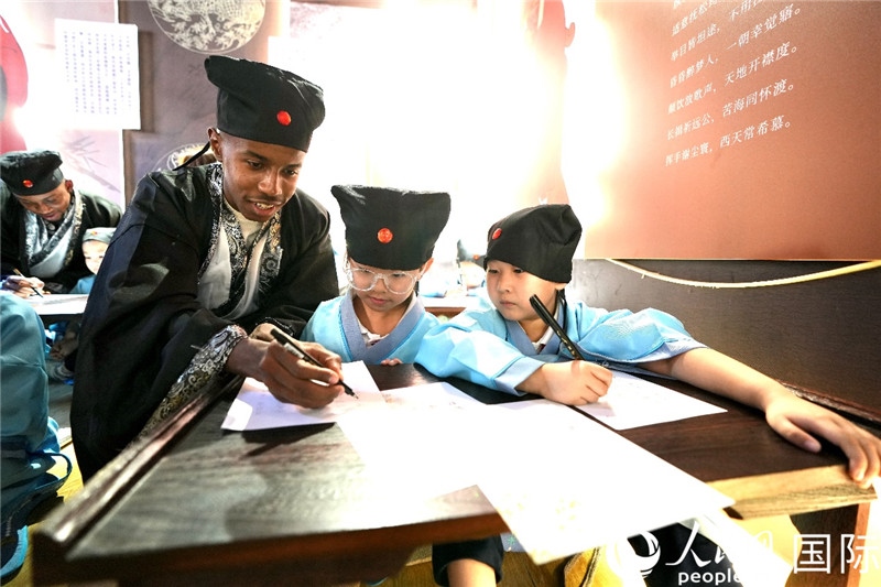 圖為選手與同學(xué)們一起寫(xiě)書(shū)法。人民網(wǎng) 盧鵬宇攝