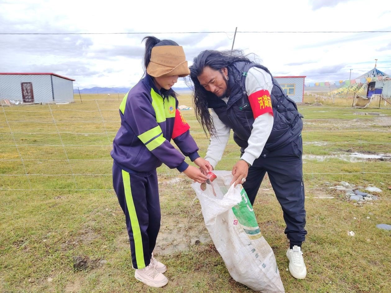 玉樹州稱多縣珍秦鎮(zhèn)河湖志愿者才培和他女兒更求拉毛在清掃垃圾。受訪者供圖
