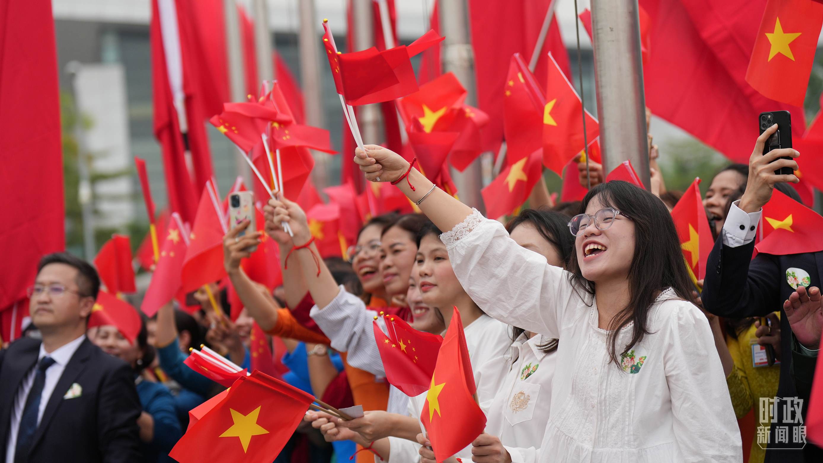 △人們揮舞兩國旗幟歡迎習(xí)近平訪越。（總臺(tái)國廣記者李晉拍攝）