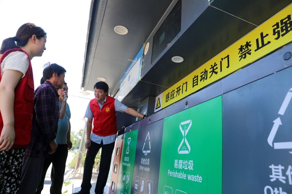 在安徽省合肥市長豐縣莊墓鎮(zhèn)棗林社區(qū)，志愿者指導(dǎo)居民使用智能垃圾分類回收設(shè)備（2023年9月1日攝）。新華社記者 曹力 攝