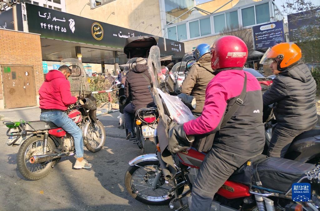 12月18日，摩托車在伊朗首都德黑蘭的一家加油站外等待加油。新華社記者 沙達提 攝