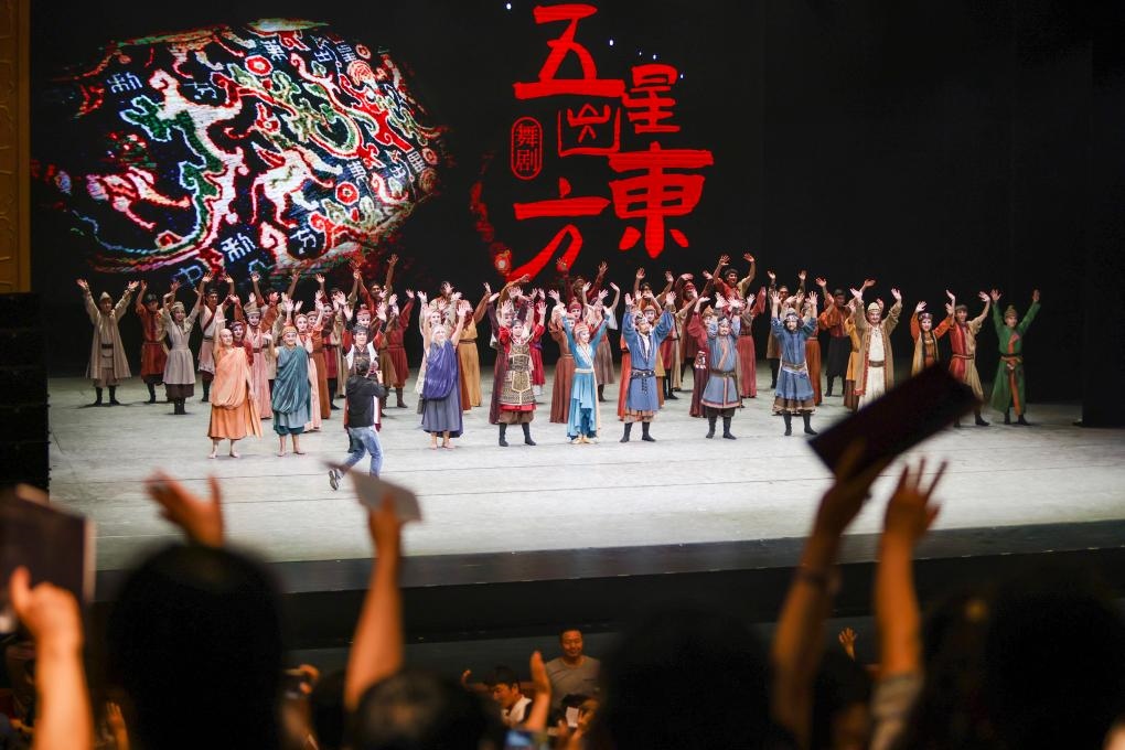 2023年7月31日，新疆和田地區(qū)新玉歌舞團(tuán)在烏魯木齊京劇院演出舞劇《五星出東方》后和觀眾互相揮手致意。這場(chǎng)演出是第六屆中國(guó)新疆國(guó)際民族舞蹈節(jié)的參演劇目之一，曾榮獲國(guó)家“文華獎(jiǎng)”等。新華社記者 郝昭 攝