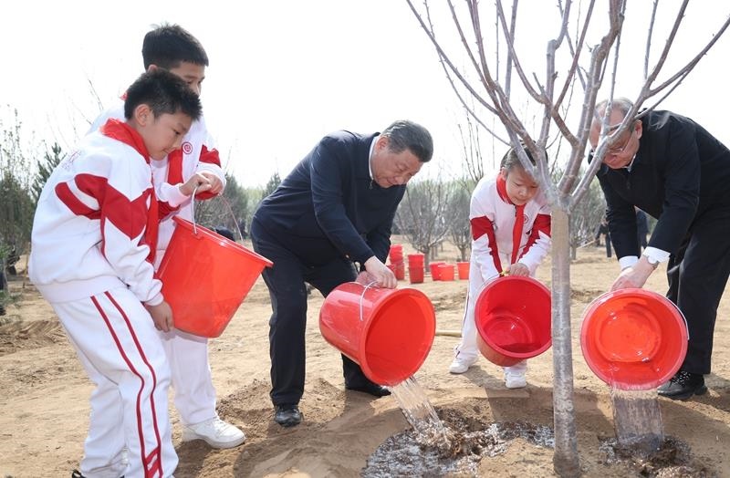 2024年4月3日，習近平總書記同少先隊員一起給剛栽下的樹苗澆水。