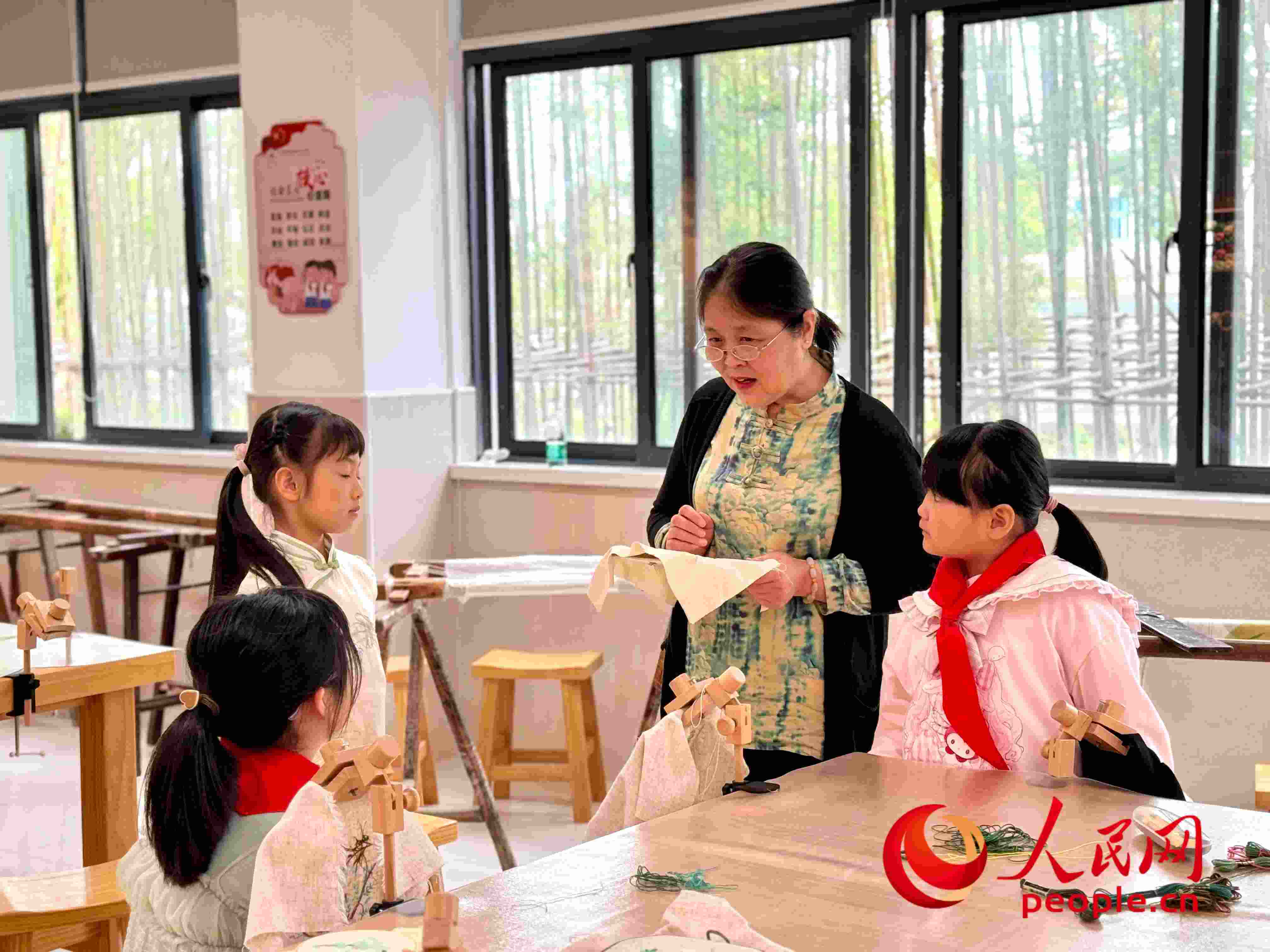 顧建珍（左三）在教孩子們刺繡知識(shí)。人民網(wǎng) 周靜圓攝