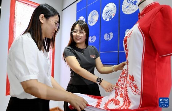5月31日，在衡水市阜城縣一家剪紙工作室，游客在觀賞帶有剪紙元素的旗袍。
