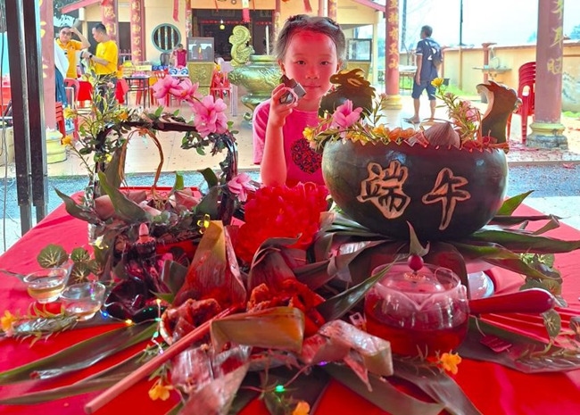小朋友展示學(xué)裹粽子的成品照。組委會供圖