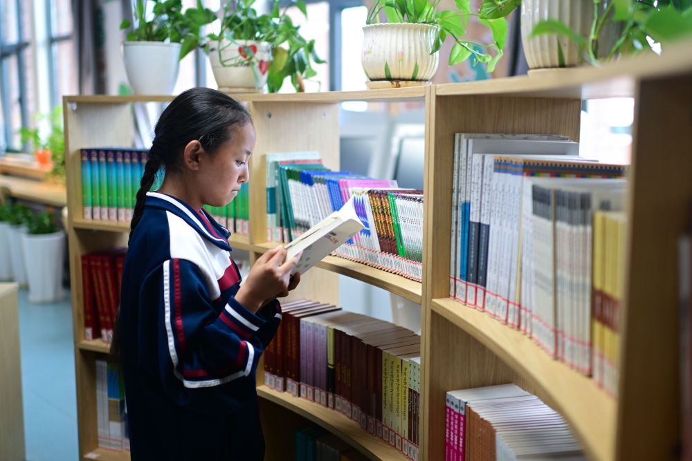6月18日，果洛西寧民族中學學生尼東拉毛在圖書室看書。