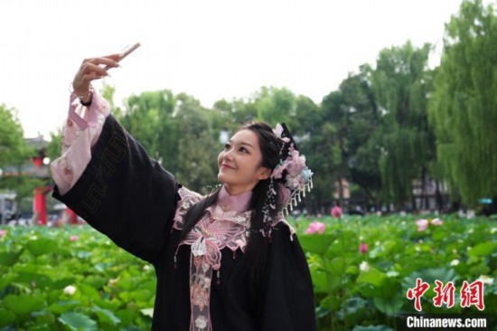 6月19日，時值一年畢業(yè)季，四川大學望江校區(qū)荷花池里的荷花盛開，成為了畢業(yè)生們的打卡圣地，吸引了眾多畢業(yè)生拍照留念。圖為畢業(yè)生在荷花池邊拍照留念。中新社記者 安源 攝
