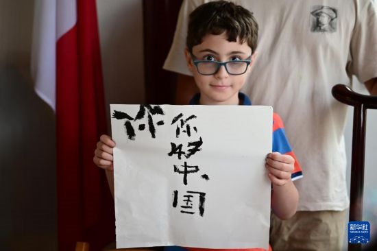 7月4日，在馬耳他桑塔露琪亞市的中國古典園林“靜園”，一名男孩展示他的書法作品。新華社發(fā)（喬納森·博格 攝）
