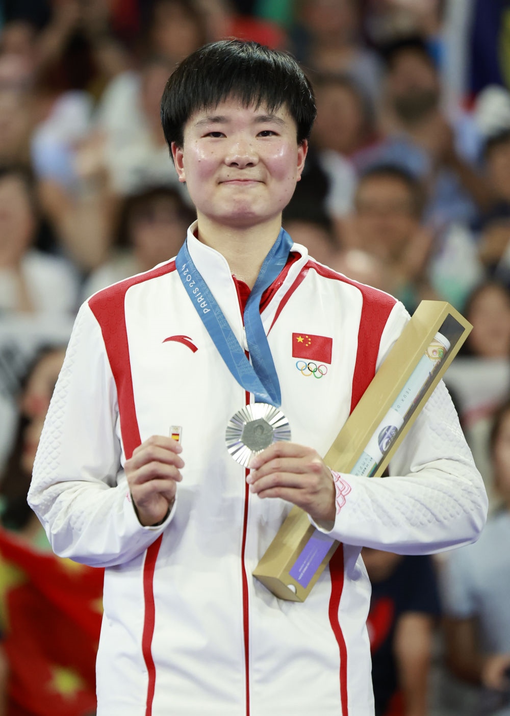 巴黎奧運會羽毛球女子單打亞軍、中國選手何冰嬌在頒獎儀式上一手握著銀牌，一手握著西班牙奧委會徽章（2024年8月5日攝）。新華社記者 任正來 攝
