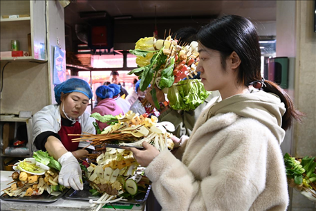 游客挑選好麻辣燙菜品后排隊等待加工。新華社記者 范培珅 攝