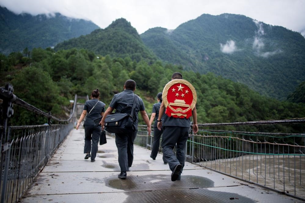 云南省怒江傈僳族自治州貢山縣人民法院法官鄧興背著國徽與同事們跨過怒江（2019年8月30日攝）。怒江高山峽谷眾多，交通不便，為方便群眾、更好地開展法律服務(wù)，背著國徽攀高山、過索橋、躲落石、鉆老林……成為鄧興法官的工作常態(tài)。新華社記者 江文耀 攝