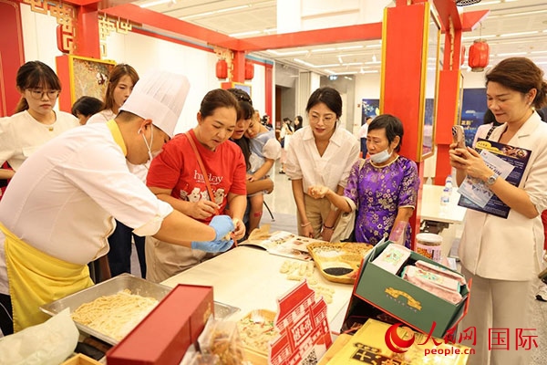 演出前，在天津桂發(fā)祥十八街麻花制作技藝非遺體驗展臺前，泰國民眾體驗天津麻花制作。人民網(wǎng)記者 楊一攝