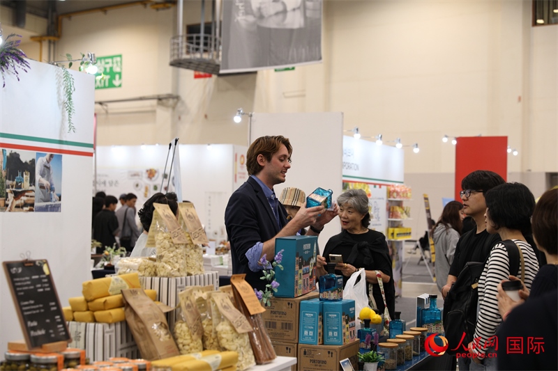 當(dāng)?shù)貢r(shí)間10月5日，在第21屆釜山國(guó)際美食博覽會(huì)上，意大利展商向參觀者們介紹的意大利食品。人民網(wǎng)記者 莽九晨攝
