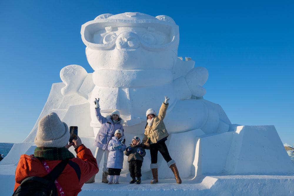 2025年1月3日，在黑龍江哈爾濱冰雪大世界園區(qū)，游客與亞冬會(huì)吉祥物雪雕“濱濱”合影