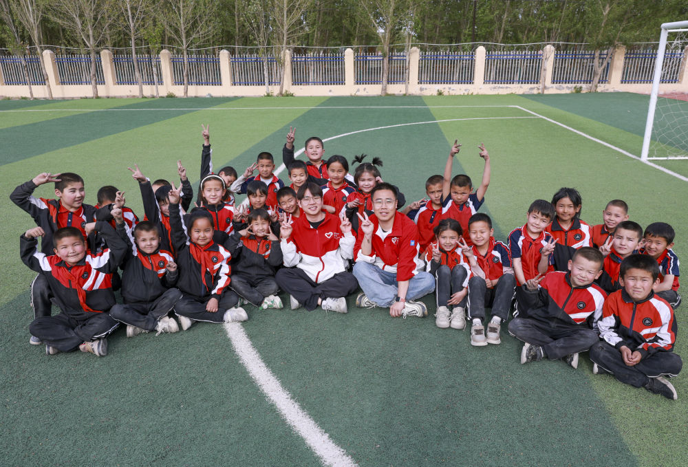 4月23日，在新疆克州阿圖什市哈拉峻鄉(xiāng)謝依特小學(xué)，支教教師王俊文（中左）、李軻凡（中右）和學(xué)生在一起。